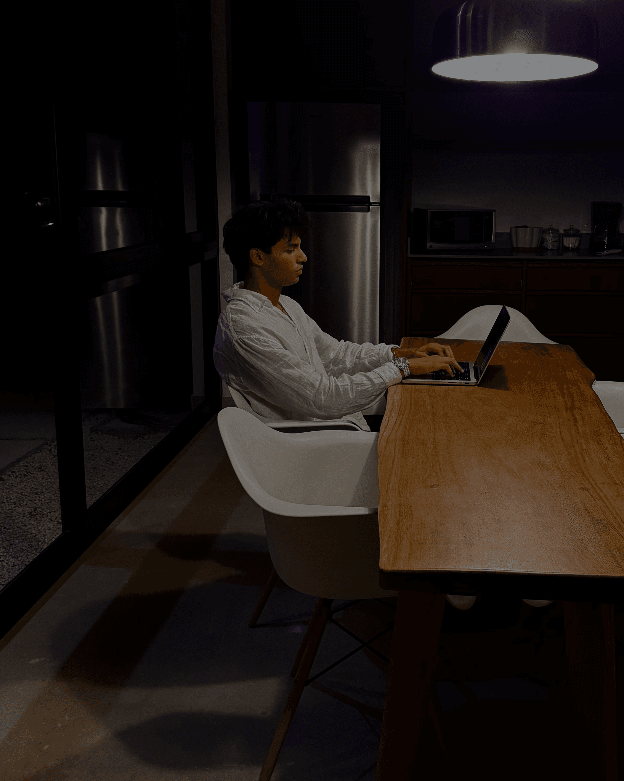 Ari Shah working on a laptop at a kitchen table at night